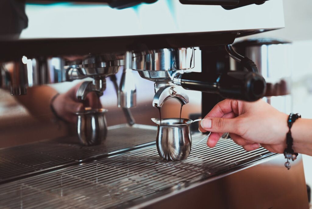 Close-up of a hand preparing espresso with a coffee machine in a café.
